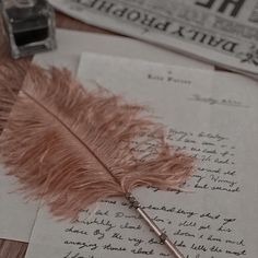 a feather quill sitting on top of a piece of paper next to a pen