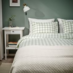 a bedroom with green walls and white bedding in the corner, along with a lamp