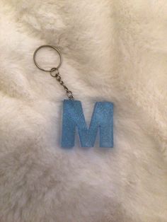 a keychain with the letter m on it is laying on a fur surface