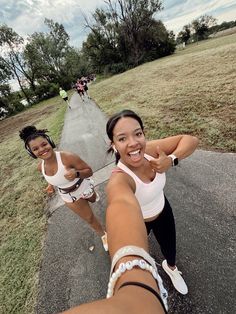 two women are taking a selfie on the street while another woman is running behind them