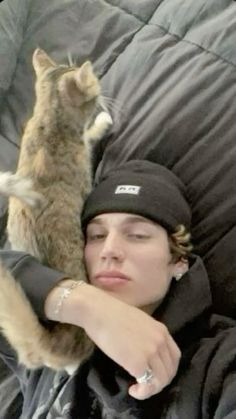 a woman laying on top of a couch next to a cat