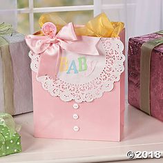 pink gift bags with bows and lace on them sitting next to presents in front of a window