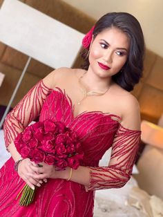 a woman in a red dress holding a bouquet of flowers and posing for the camera