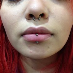 a woman with red hair and piercings on her nose