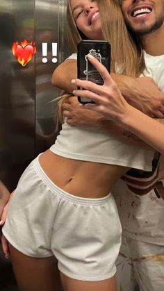 two people hugging each other in front of an open elevator door, one holding a cell phone