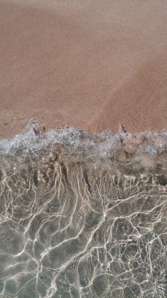 the sand and water are reflecting on the beach shore line, as seen from above