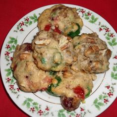 a white plate topped with cookies on top of a red table covered in holly leaves