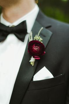 a man wearing a black tuxedo with a red flower on it's lapel