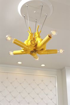 a yellow chandelier hanging from the ceiling in a room with white wallpaper