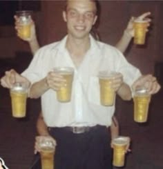 a man is holding up two mugs of beer