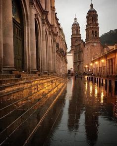 an image of a city street that is very wet and rainy at night with people walking on the sidewalk