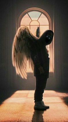 an angel standing in front of a window with its wings spread out and looking at the ground