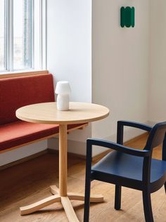 two chairs and a table in a room with wood flooring, one chair has a white vase on it