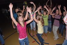 a group of young people standing on top of a dance floor with their hands in the air