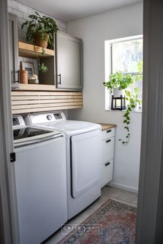 a washer and dryer in a small room next to a window with potted plants