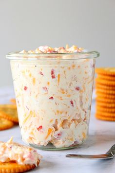 a glass jar filled with food sitting on top of a table next to crackers