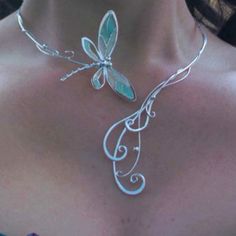 a woman wearing a silver necklace with a dragonfly on it's back neck