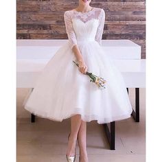 a woman in a white dress standing next to a table