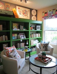 a living room with green bookcases and white chairs in front of a window