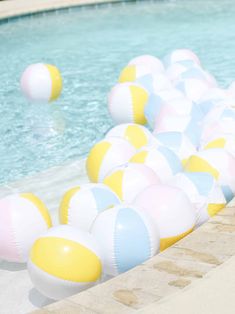 large inflatable beach balls are lined up along the edge of a swimming pool