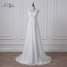 a white wedding dress on a mannequin stand in front of a wall with wood flooring