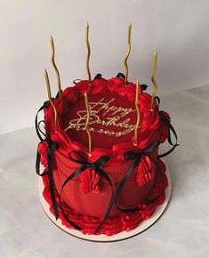 a red and gold birthday cake with candles on top