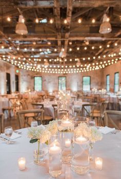 the tables are set with white flowers and lit candles for an elegant dinner or reception