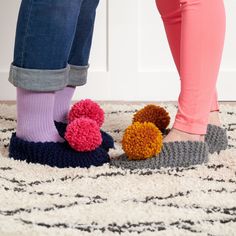 two people wearing slippers with pom - poms on them standing next to each other