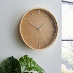 a wooden clock on the wall next to a potted plant and window sill