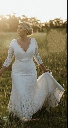 a woman in a white dress is walking through the grass with her hands behind her back