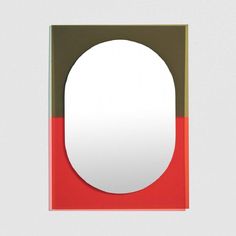 an oval shaped mirror with a red and green border around the edge, on a white background