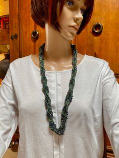 Two strands, each beaded individually and made up of 10 strands each.  The two large strands are then wrapped around each other.  Shades of green wit a bit of purple. Lobster claw clasp. Necklace can be worn long or wrapped are the neck twice as a choker.  Total length : 30" Width 1" Handmade Green Beaded Lariat Necklaces, Handmade Green Lariat Beaded Necklace, Green Multi-strand Hand-strung Beaded Necklaces, Green Multi-strand Hand-strung Necklaces, Green Braided Bohemian Jewelry, Adjustable Green Double Strand Beaded Necklace, Handmade Green Multi-strand Beaded Necklaces, Handmade Green Multi-strand Beaded Necklace, Adjustable Green Handwoven Necklace