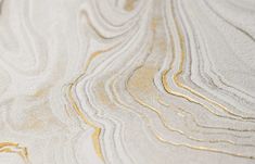 closeup of white and gold marbled surface with wavy lines in the center, as seen from above