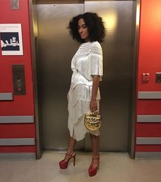 a woman standing in an elevator with her hand on her hip and holding a purse