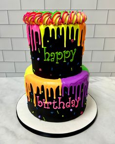 three tiered birthday cake decorated with colorful icing and sprinkles