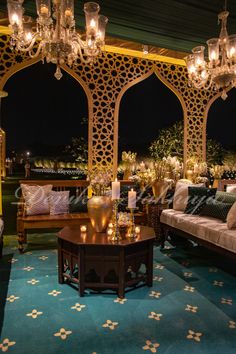 a living room with couches and chandeliers hanging from the ceiling at night