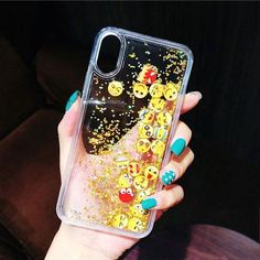 a woman's hand holding up a phone case with smiley faces and glitter on it