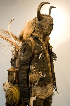 a man with horns and fur on his head is dressed in an outfit made out of old clothing