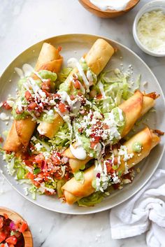 a white plate topped with lots of food next to a bowl filled with sauces