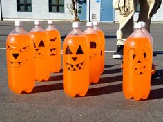 four plastic bottles with faces painted on them are lined up in the middle of a parking lot