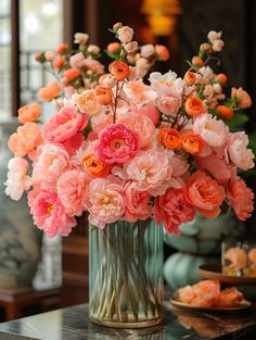 a vase filled with pink and orange flowers on top of a table next to plates