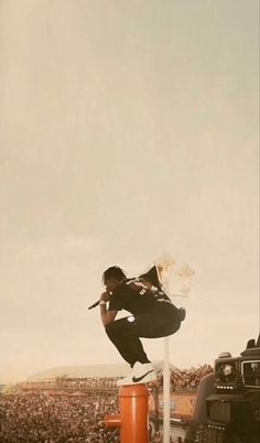 a man is doing tricks on top of a pole in front of a large crowd