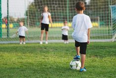 a group of children playing soccer on a field with one boy kicking the ball around