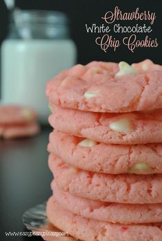 a stack of pink cookies next to a glass of milk