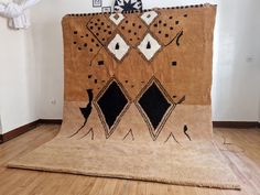 a brown and black area rug sitting on top of a hard wood floor next to a white wall