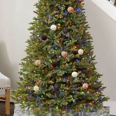 a christmas tree with lights and presents under the stairs