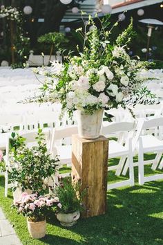 an outdoor ceremony with white chairs and flowers