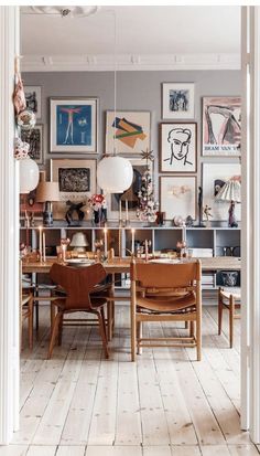 a dining room table with chairs and pictures on the wall above it, along with other furniture