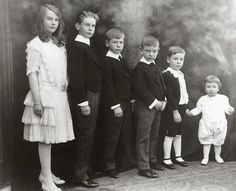 a group of children standing next to each other in front of a black and white photo