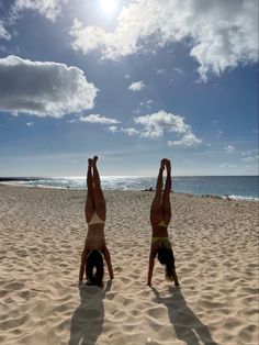 two women are doing yoga on the beach